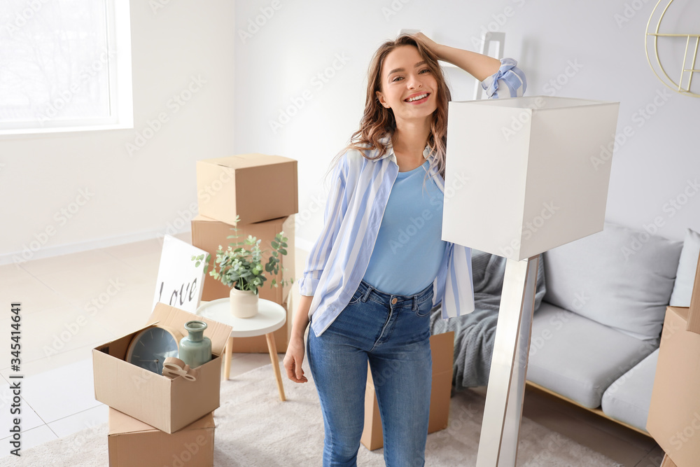 Happy young woman with belongings in her new home Happy young woman with belongings in her new home