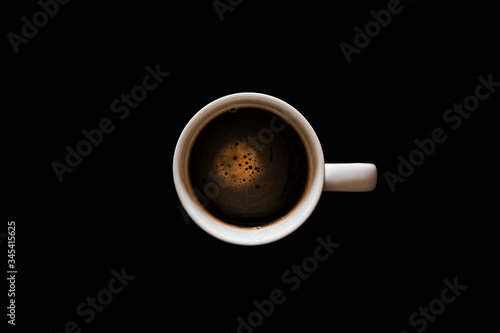 Cup with coffee on black background. Morning coffee top view.