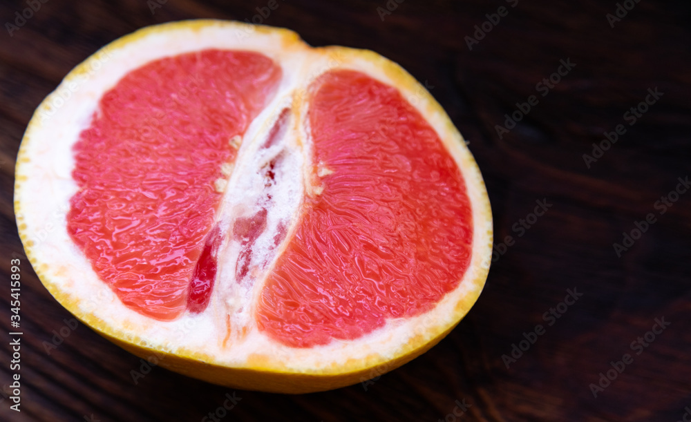 Half a yellow red grapefruit on a dark wooden table. Half a yellow red grapefruit on a dark wooden table.