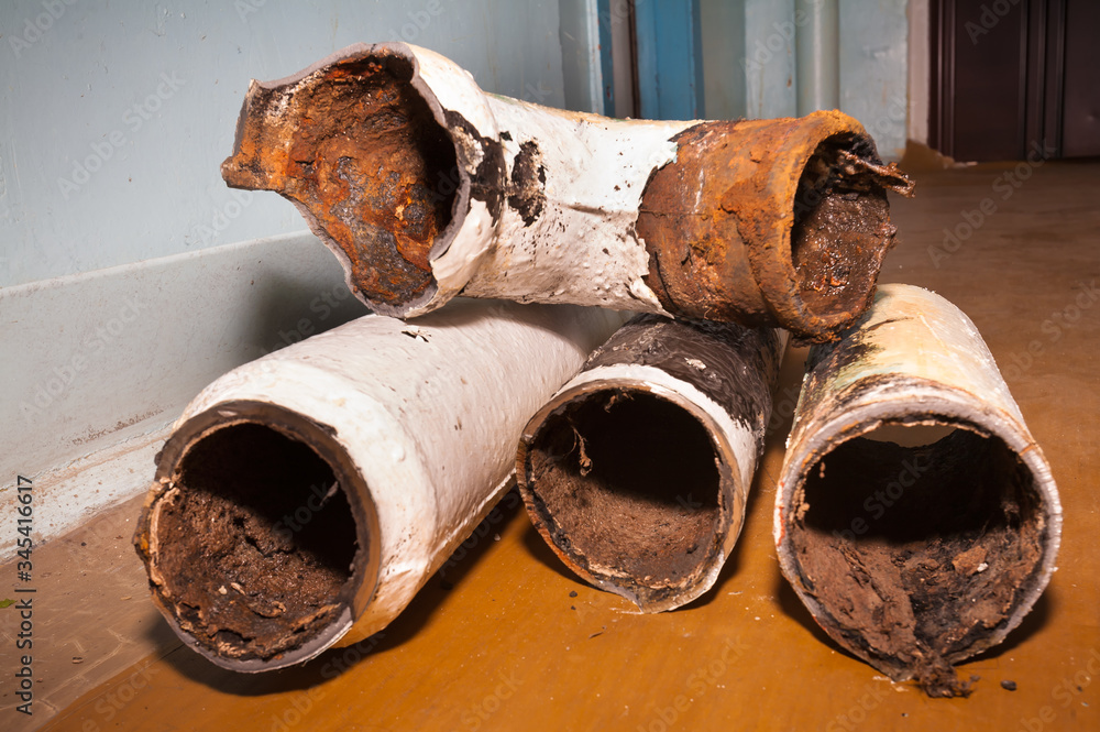 Replacing old sewer pipes in an apartment of a multi-storey residential building. The dismantled old cast-iron pipes are cut into pieces and stacked on the floor. Color image.
