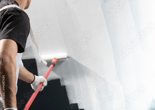 Fotografija Male decorator painting a wall