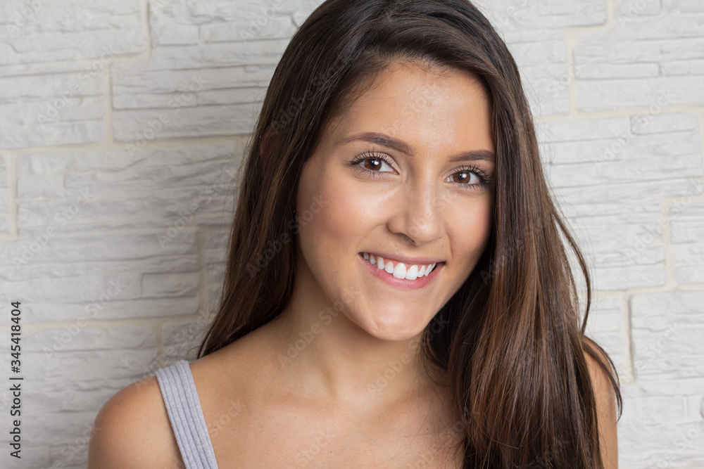 Portrait of Young pretty woman looking at camera and smiling. Closeup. Isolated on white brick wall Portrait of Young pretty woman looking at camera and smiling. Closeup. Isolated on white brick wall