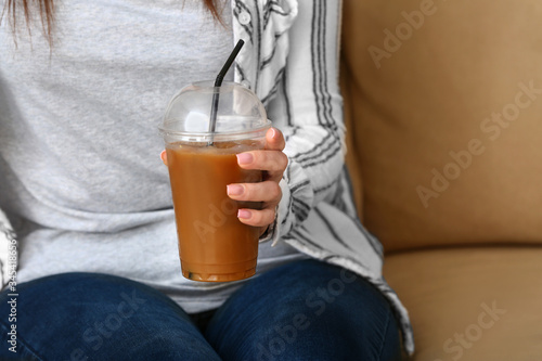 Woman with cup of tasty iced coffee in cafe, closeup