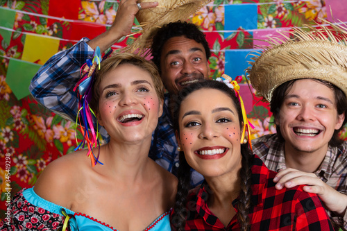 Happy cheerfulfun friends together dressed in plaid clothes smiling broadly at evening party. Traditional brazilian june festival, party, celebration concept. photo