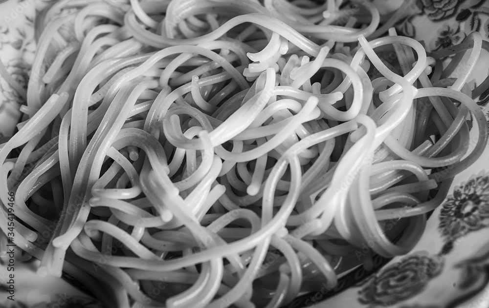 Boiled vermicelli - spaghetti in a plate. Black and white image. Soft focus.