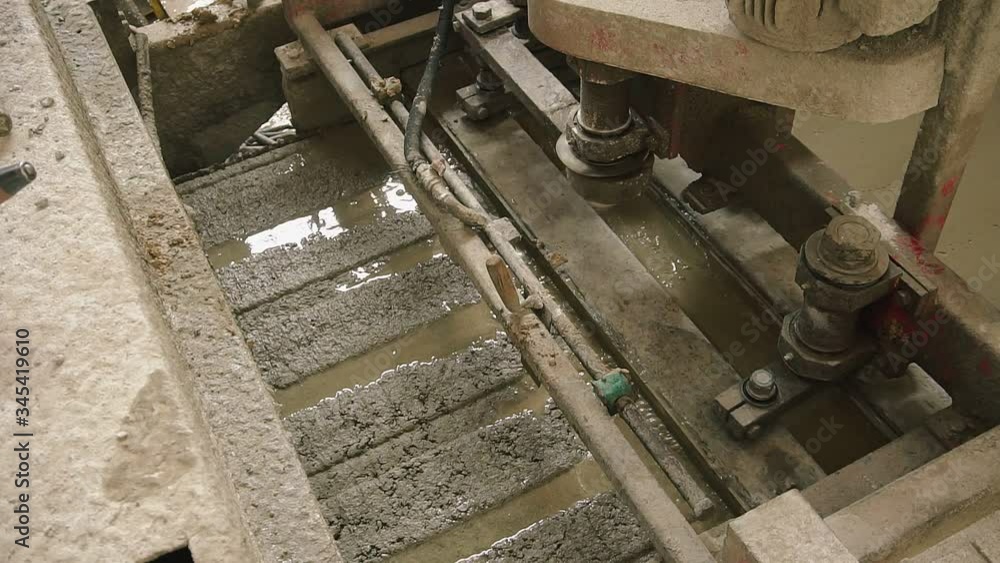 Machine forming concrete and making smooth top. The concrete solution is poured into the formwork. Manufacture of reinforced concrete wall panels. Closeup Machine forming concrete and making smooth top. The concrete solution is poured into the formwork. Manufacture of reinforced concrete wall panels. Closeup