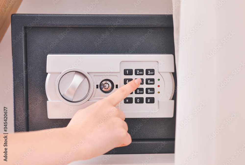Woman opening modern safe indoors Woman opening modern safe indoors