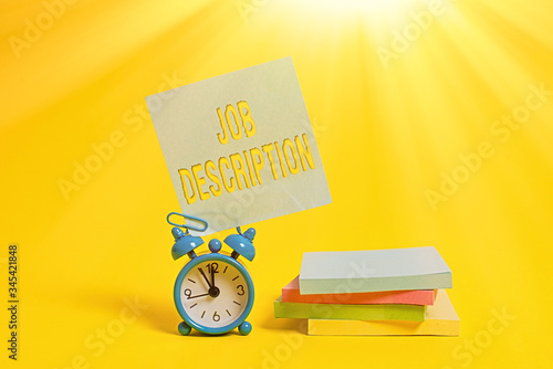 Handwriting text writing Job Description. Conceptual photo A document that describes the responsibilities of a position Metal alarm clock blank sticky note stacked notepads colored background photo