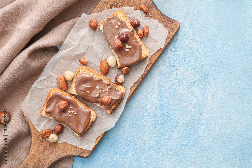 Fototapeta premium Board with fresh bread and chocolate paste on color background