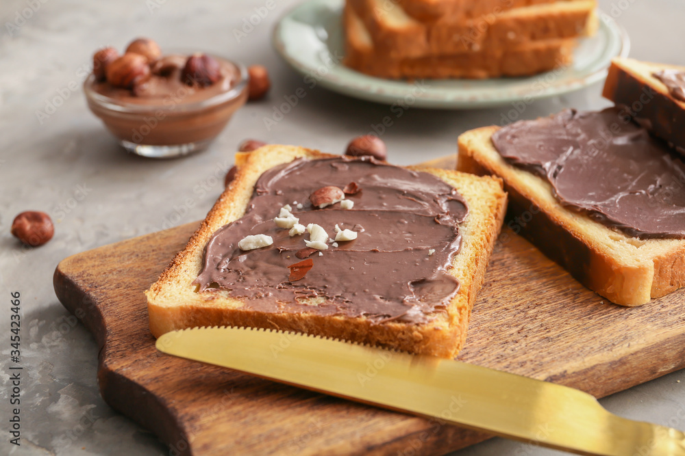 Board with fresh bread and chocolate paste on grey background Board with fresh bread and chocolate paste on grey background