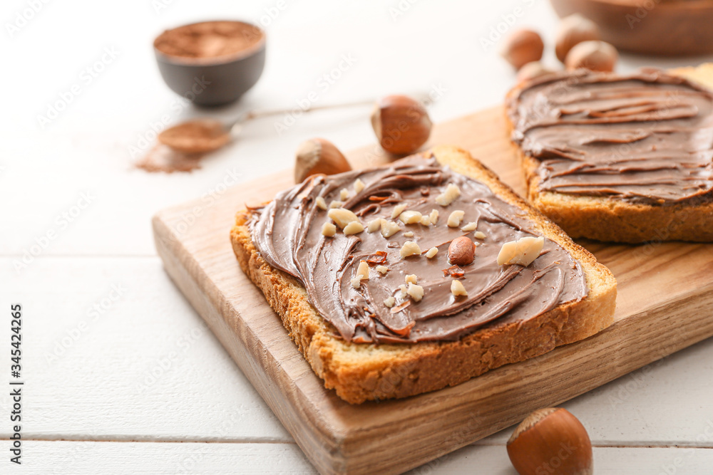Board with fresh bread and chocolate paste on table