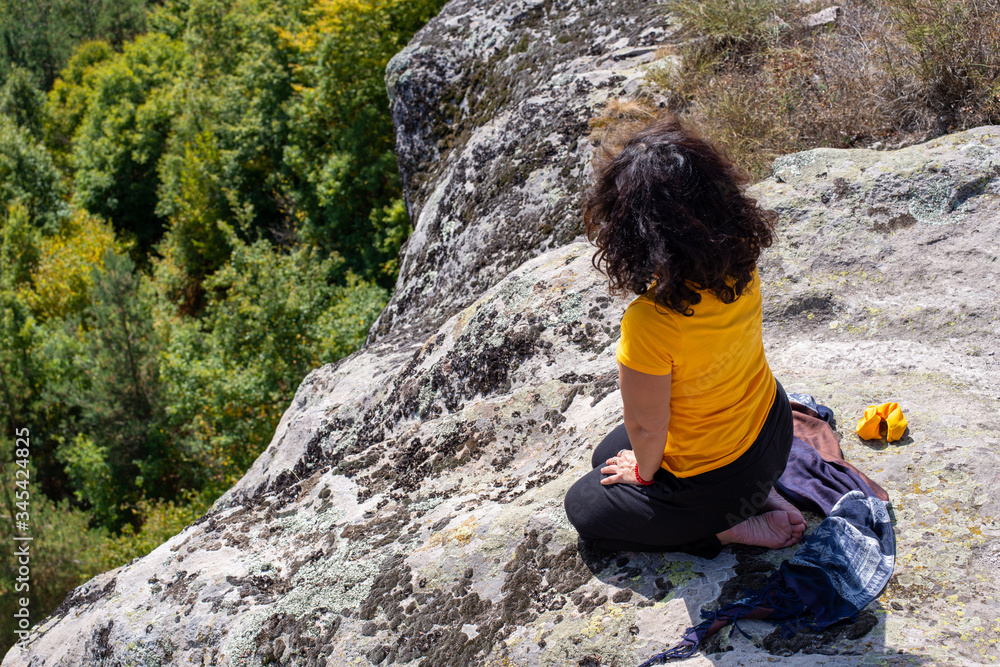 Naklejka premium Girl meditating at the edge of a ancient sacred location.
