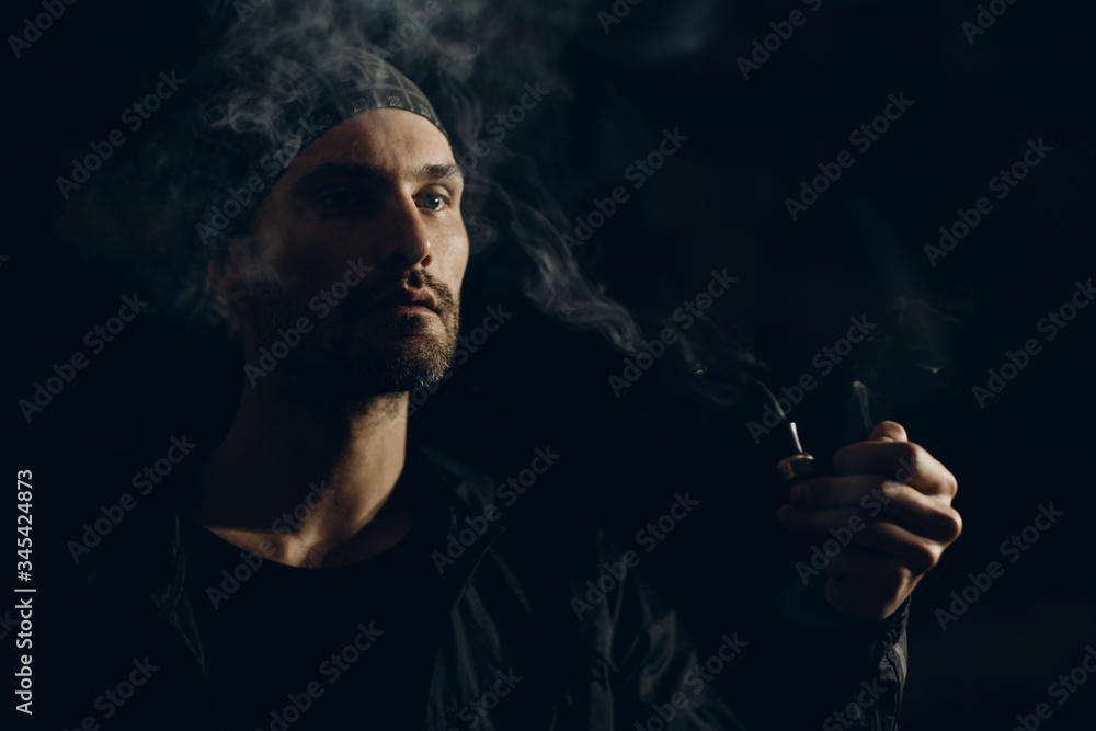 Man smoking a pipe on dark background Man smoking a pipe on dark background