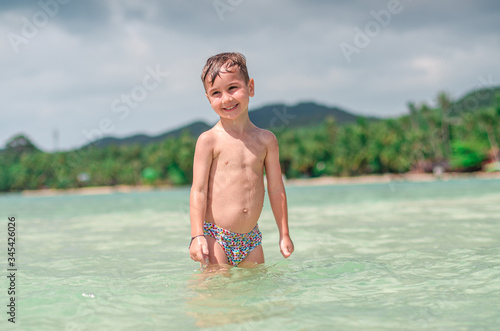 
happy child splashes on the ocean. The kid smiles and bathes in the sea. Beautiful coast of the ocean, a child is played on the seashore. Boy at the sea.
