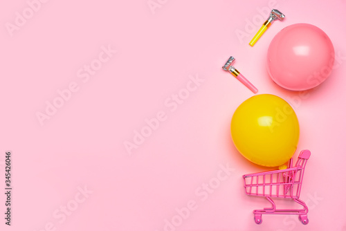 Birthday composition with shopping cart on color background