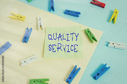 Writing note showing Quality Service. Business concept for how well delivered service conforms to client expectations Colored clothespin paper reminder with yellow blue background photo