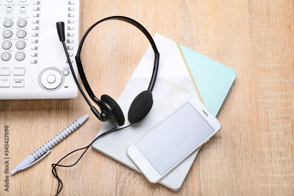 Headset, notebook and mobile phone on table of technical support agent Headset, notebook and mobile phone on table of technical support agent