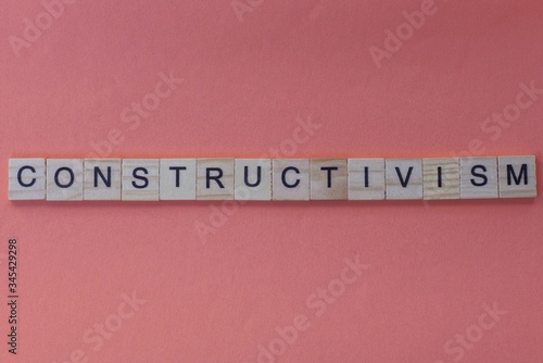  long word constructivism from gray wooden small letters with black font on an orange background photo