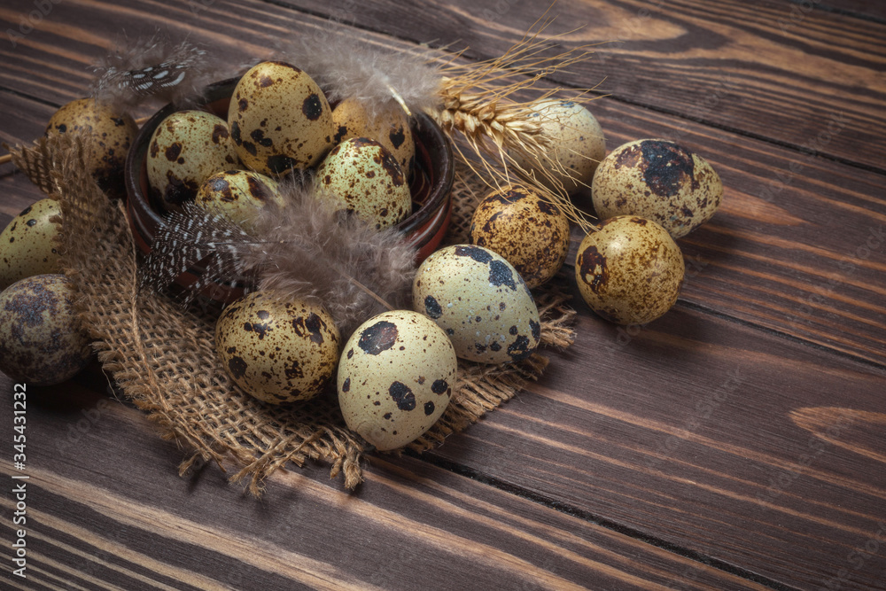 Quail eggs and feathers in a clay plate on a dark wooden background Quail eggs and feathers in a clay plate on a dark wooden background