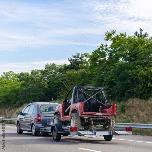 Car carrying trailer with an UTV off-road vehicle on highway road 
