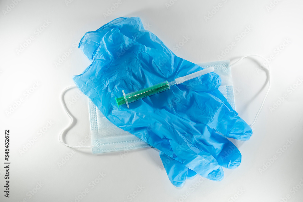 disposable blue medical mask, gloves and syringe on a white background
