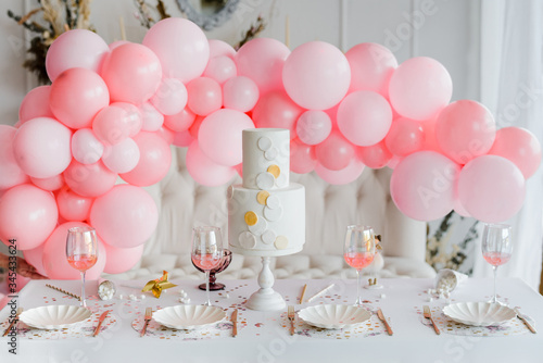 Birthday or wedding table setting in white colors with cocktails in glasses. Baby shower or girl party. Selective focus. Balloon garland