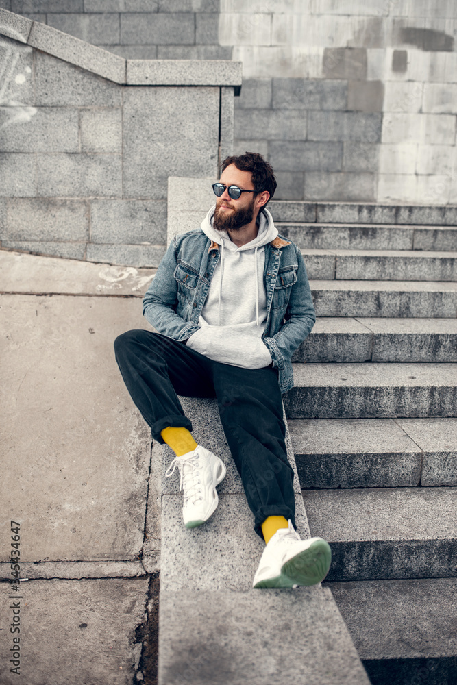 City portrait of handsome hipster guy with beard wearing gray blank hoodie or hoody with space for your logo or design. Mockup for print City portrait of handsome hipster guy with beard wearing gray blank hoodie or hoody with space for your logo or design. Mockup for print