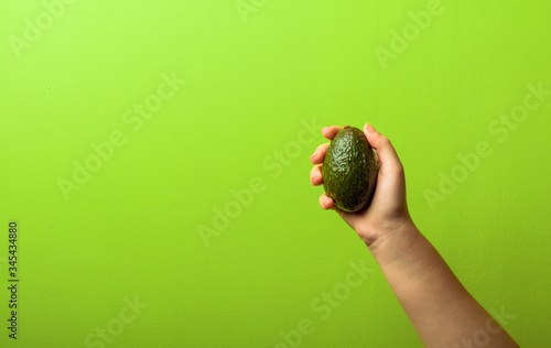 avocado in a hand of woman green background. healthy food concept