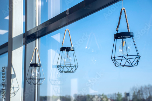 Geometric lanterns with clear blue sky and window reflections in the background.