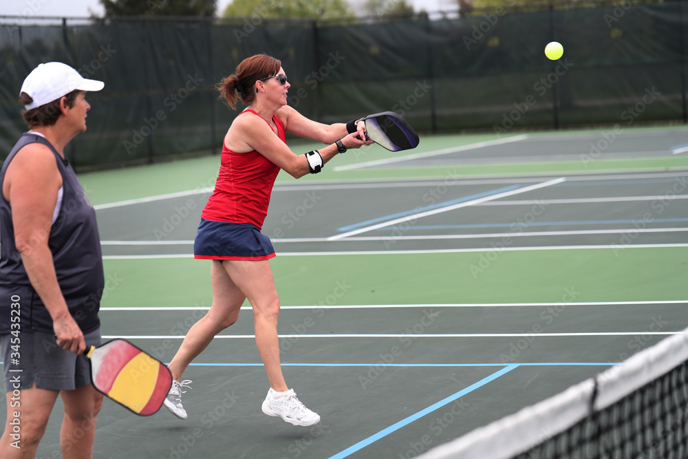 A pickleball two-handed backhand is hit by a senior during a doubles match