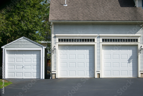 Fototapet Two cars  Garage Doors painted in white color and one car garage attached to a in a multifamily  house