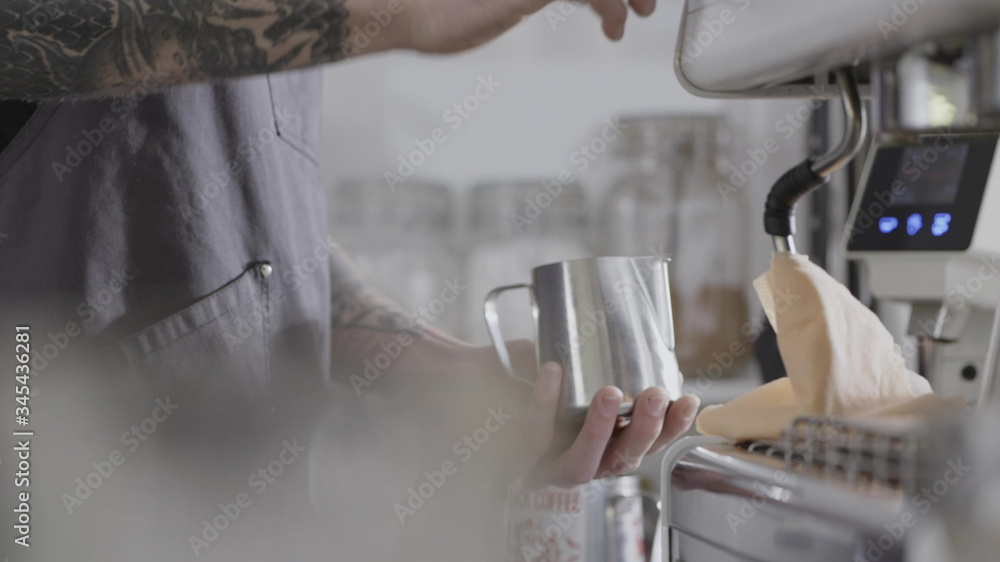 The hands of a young barista guy make steam for whipping milk in a mug. Full HD video, 240fps, 1080p.