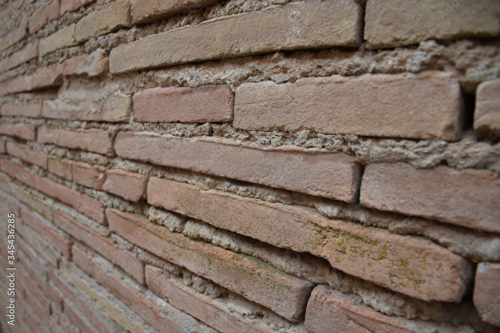 Pared de ladrillo rústico y tonos marrones, cuyas lineas convergen fuera de plano.