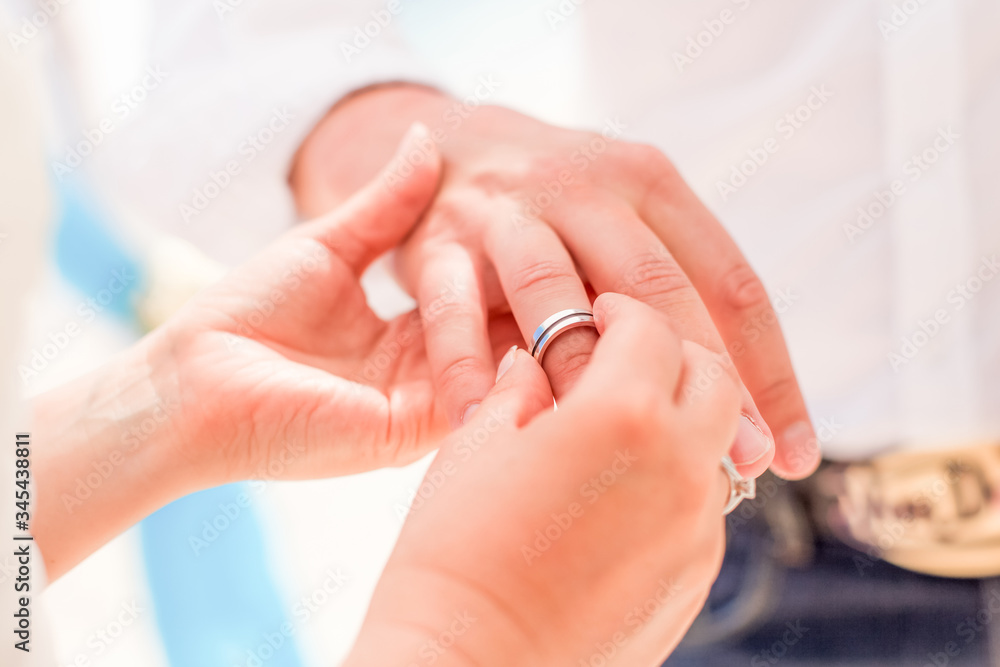 Bride and groom exchanging wedding rings close up during symbolic nautical decor destination wedding marriage on sandy beach in front of the ocean in Punta Cana, Dominican republic Bride and groom exchanging wedding rings close up during symbolic nautical decor destination wedding marriage on sandy beach in front of the ocean in Punta Cana, Dominican republic