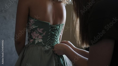 woman tying the laces of the corset evening dresses green with pink flowers