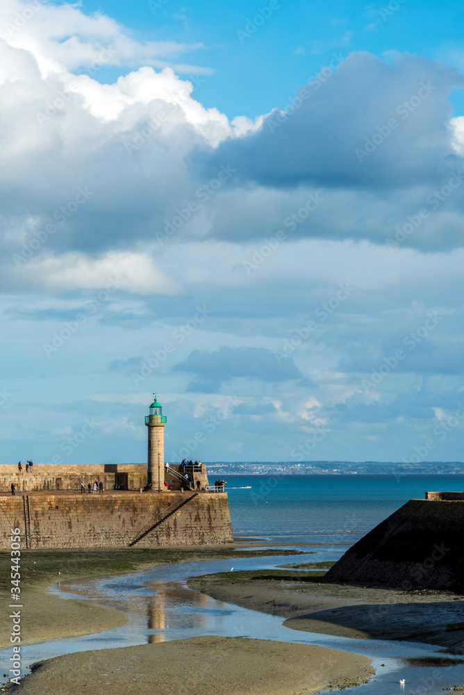 view of a harbor in Brittany, France, during a low tide, with a green roof lighthouse