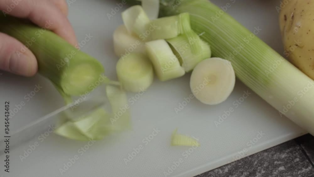 Hand slicing leek vegetable with knife close up overhead shot Hand slicing leek vegetable with knife close up overhead shot