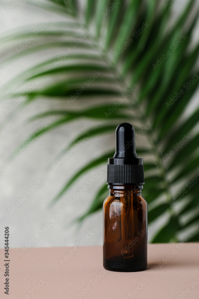 Amber glass dropper bottle with essential oil and tropical leaf. Natural herbal cosmetic product, aromatherapy message oil. Amber glass dropper bottle with essential oil and tropical leaf. Natural herbal cosmetic product, aromatherapy message oil.