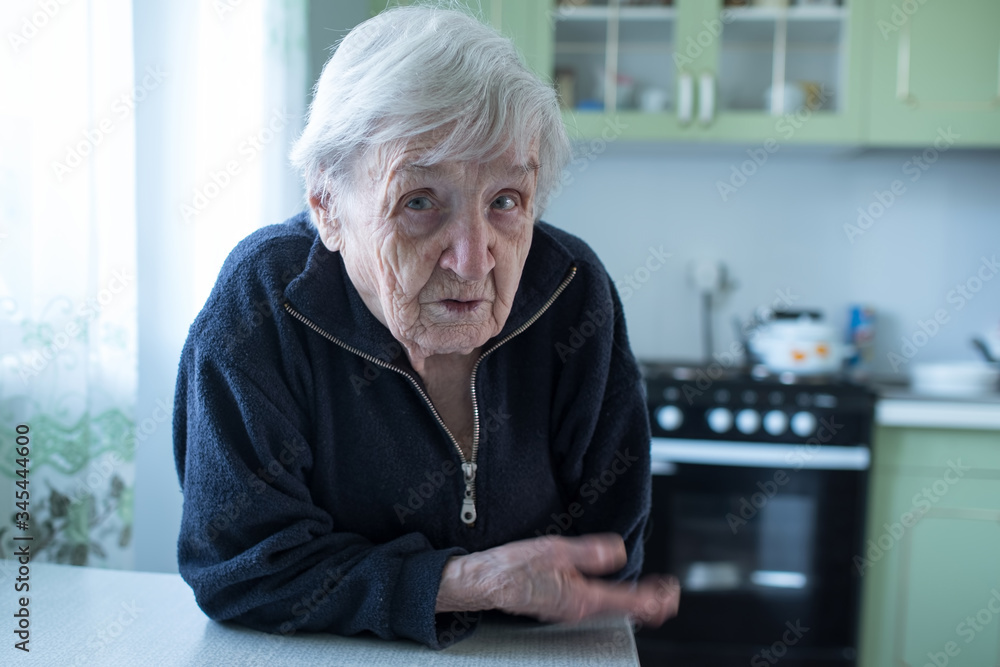 An elderly woman portrait near window in the house. An elderly woman portrait near window in the house.