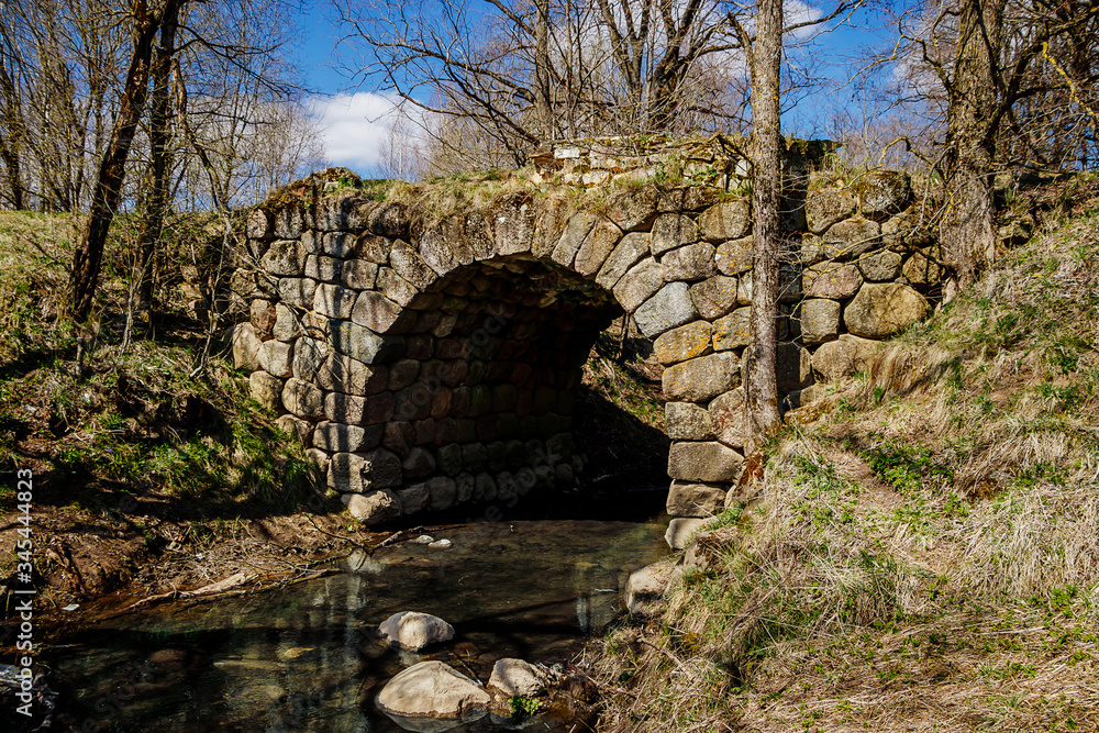Ancient stone bridge over the river against the blue sky. Vintage Romanesque architecture. Ancient stone bridge over the river against the blue sky. Vintage Romanesque architecture.