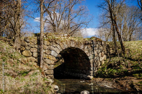 Ancient stone bridge over the river against the blue sky. Vintage Romanesque architecture.