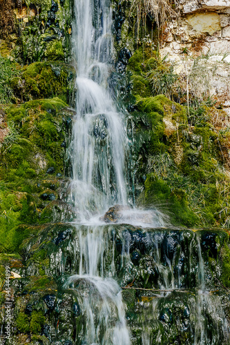 Beautiful mountain waterfall among the stones. A source of water in arid areas. Motion blur  vertical photo