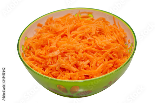 Shredded carrots in a bowl on a white background. Vegetable carrot salad in a green plate.