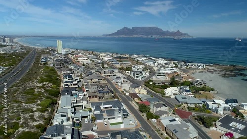 Corona virus lockdown, Cape Town, South Africa:  Side tracking aerial at Small Bay, Bloubergstrand, with empty beach and streets with Table Mountain in the background, Cape Town, South Africa.