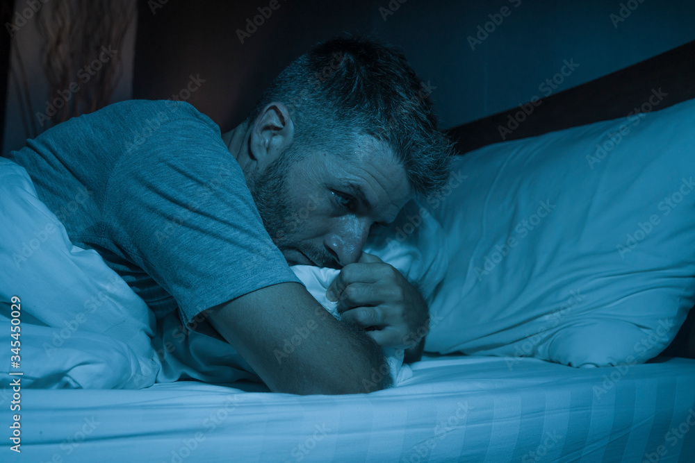 dramatic portrait in the dark of attractive depressed and worried man on bed suffering depression crisis and anxiety feeling lost lying sleepless in insomnia and life problem concept dramatic portrait in the dark of attractive depressed and worried man on bed suffering depression crisis and anxiety feeling lost lying sleepless in insomnia and life problem concept