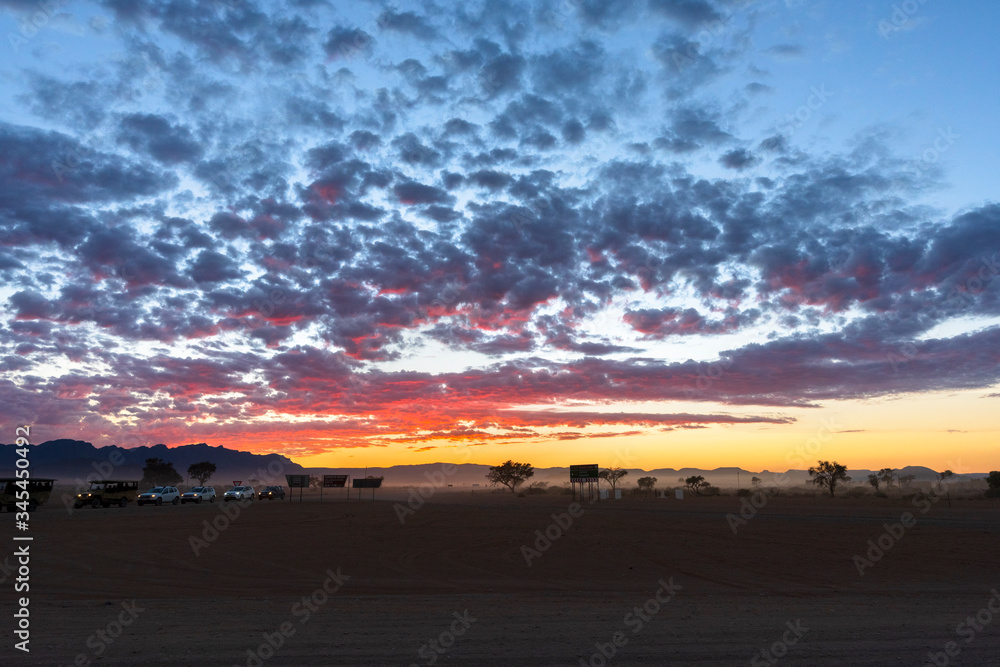 SESRIEM, NAMIBIA - APRIL 15, 2019: Car caravans safari at national park at sunrise scene. 