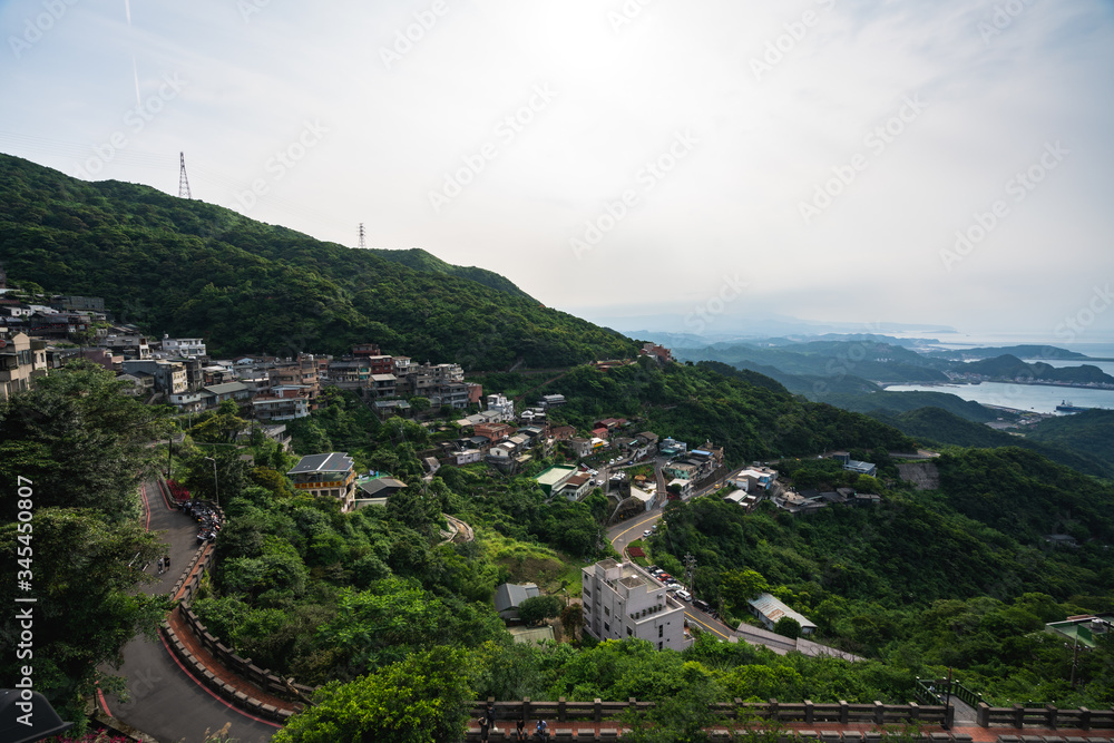 Scenic Panoramic View of Village sitting on the side of a mountain during cloudy weather with a view of distant islands 