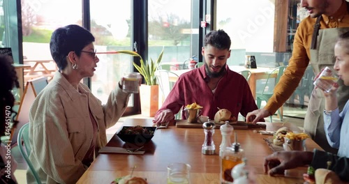 Waiter serving food to multi-ethnic group of friends at restaurant