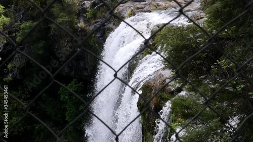 Rainbow Falls in Kerikeri River New Zealand behind a chainlink fence slow motion, Handheld dolly right photo