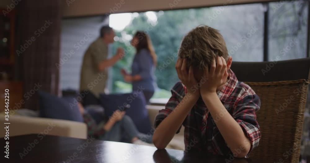 Caucasian boy sitting at a table with his head in his hands Caucasian boy sitting at a table with his head in his hands